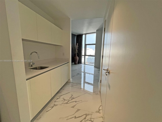 kitchen with white cabinets, a wall of windows, and sink