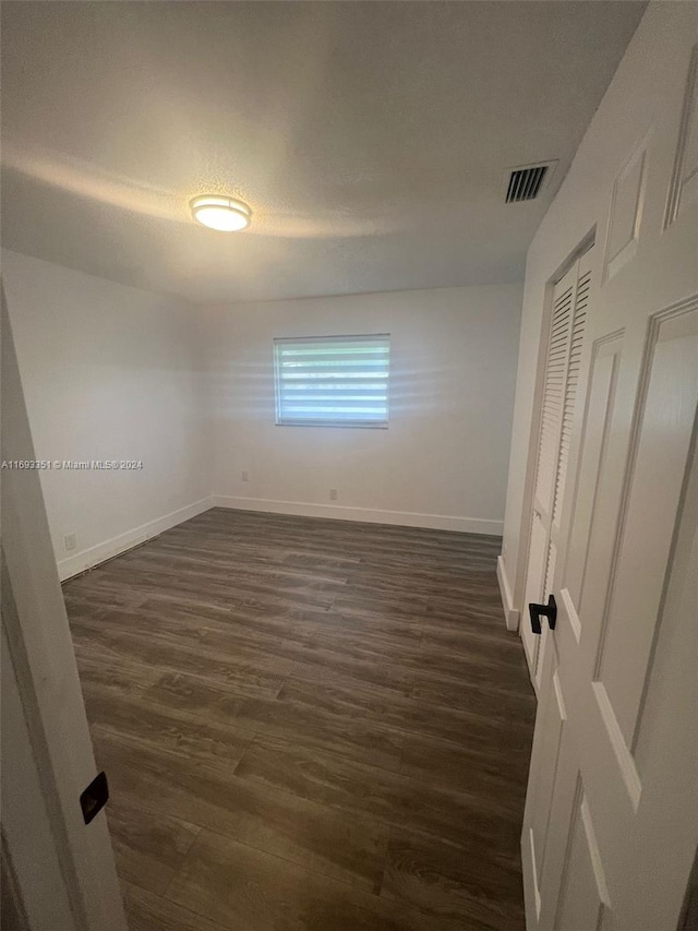 718 Whippoorwill Ln, Delray Beach, FL 33445 - unfurnished bedroom featuring dark wood-style floors, baseboards, and a closet