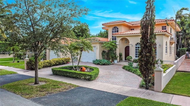 mediterranean / spanish-style home with decorative driveway, stucco siding, an attached garage, fence, and a tiled roof