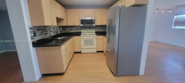 kitchen with decorative backsplash, appliances with stainless steel finishes, light wood-type flooring, and sink