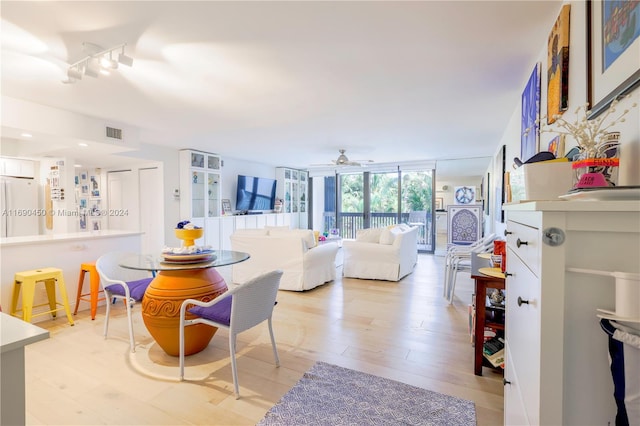 dining space featuring a wall of windows, light hardwood / wood-style flooring, and ceiling fan