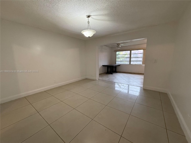 empty room with a textured ceiling, ceiling fan, and light tile patterned flooring