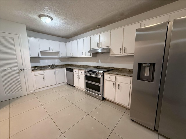 kitchen with appliances with stainless steel finishes, a textured ceiling, sink, light tile patterned floors, and white cabinetry