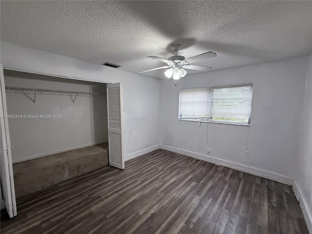 unfurnished bedroom with a textured ceiling, ceiling fan, a closet, and dark hardwood / wood-style floors