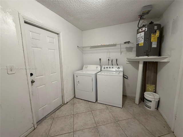 clothes washing area with water heater, light tile patterned flooring, a textured ceiling, and independent washer and dryer