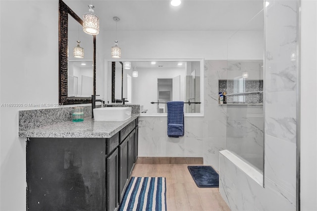 bathroom featuring a shower, hardwood / wood-style floors, vanity, and tile walls