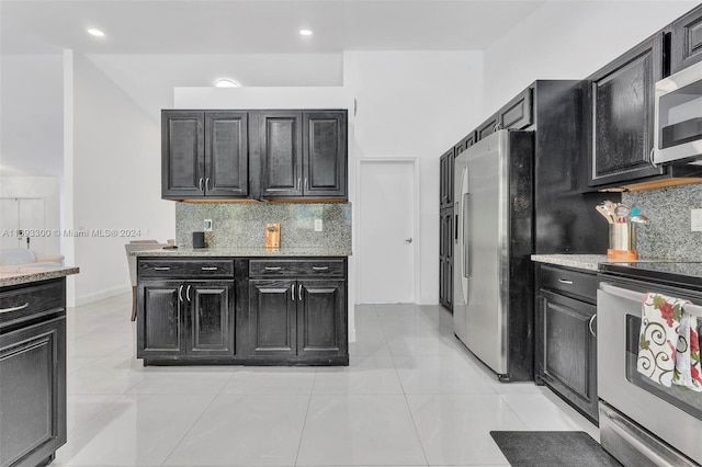 kitchen featuring decorative backsplash, appliances with stainless steel finishes, light stone countertops, and light tile patterned flooring