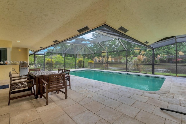 view of pool featuring glass enclosure and a patio