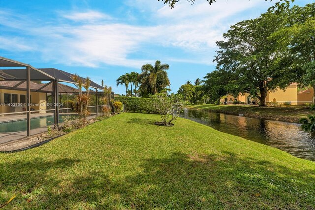 view of yard featuring a lanai, a water view, and a fenced in pool