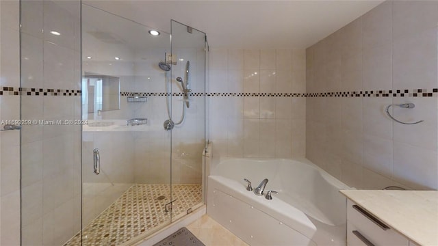 bathroom with separate shower and tub, tile patterned floors, vanity, and tile walls