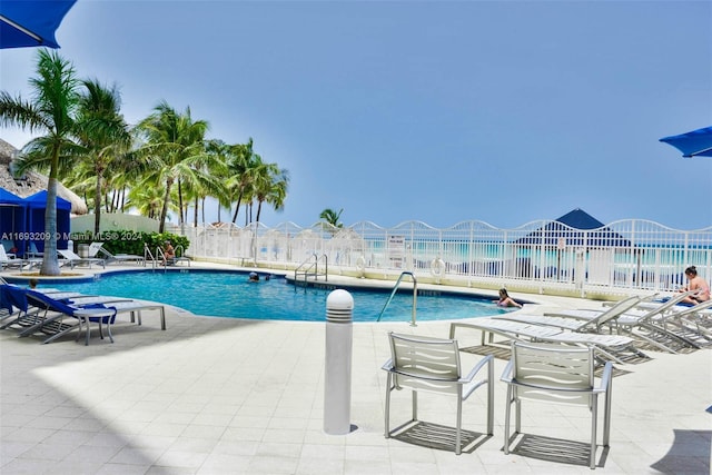 view of pool featuring a water view and a patio area