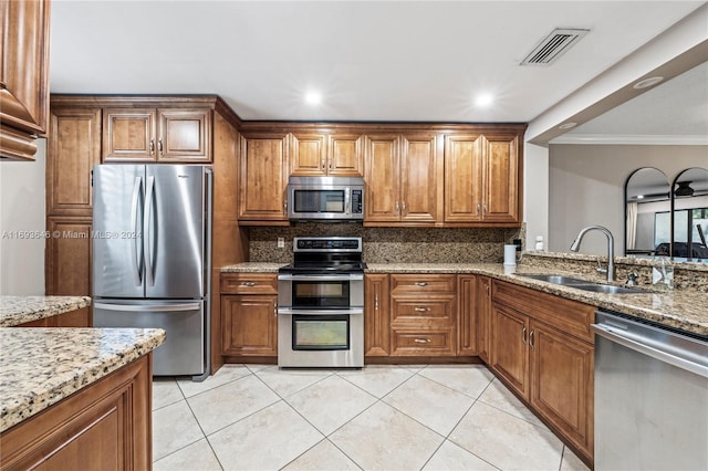 kitchen with appliances with stainless steel finishes, backsplash, light stone counters, crown molding, and sink