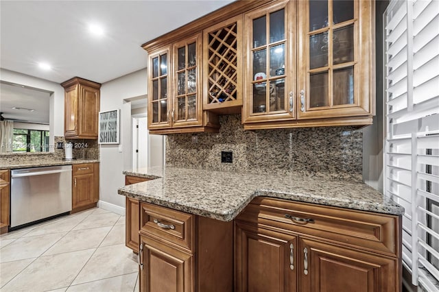 kitchen featuring light stone countertops, light tile patterned floors, tasteful backsplash, and stainless steel dishwasher