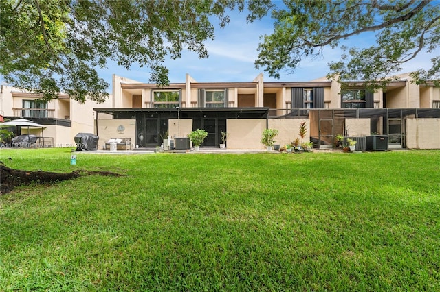 rear view of property featuring central AC unit and a lawn