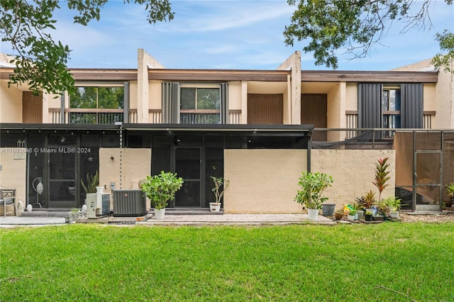 rear view of house featuring a lawn and central AC unit