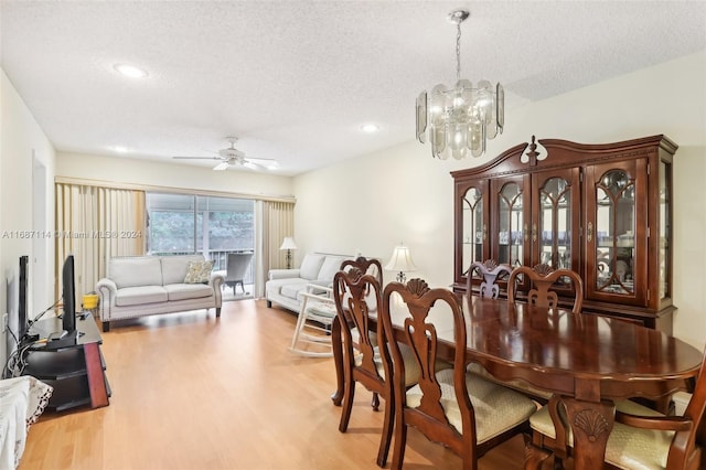 dining space with ceiling fan with notable chandelier, a textured ceiling, and light hardwood / wood-style floors