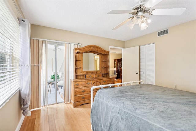 bedroom with access to outside, hardwood / wood-style flooring, ceiling fan, a textured ceiling, and a closet