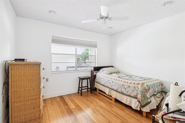 bedroom with hardwood / wood-style floors, a textured ceiling, and ceiling fan