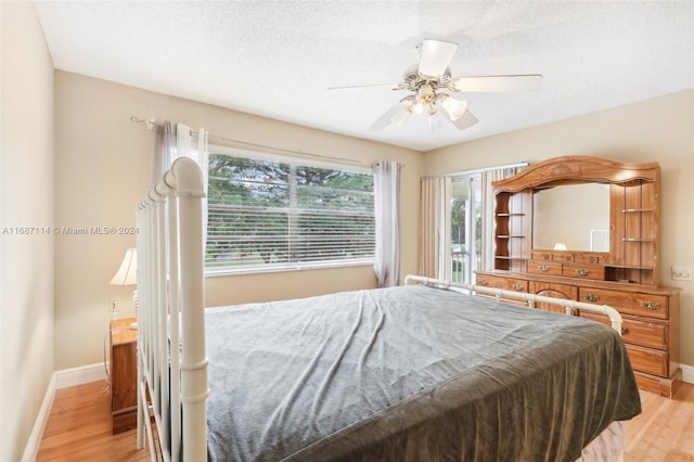 bedroom featuring ceiling fan, light hardwood / wood-style flooring, and a textured ceiling