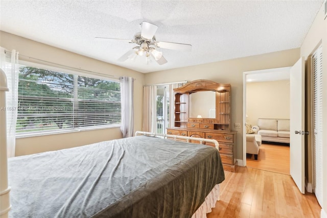 bedroom with ceiling fan, a textured ceiling, and light hardwood / wood-style flooring