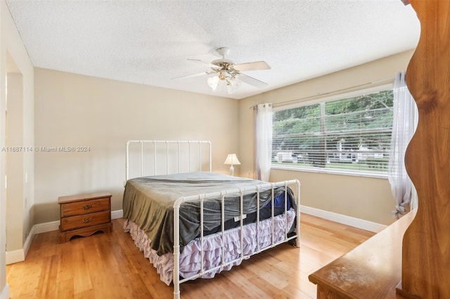 bedroom featuring hardwood / wood-style floors, ceiling fan, and a textured ceiling