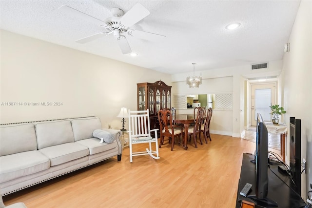 living room with a textured ceiling, hardwood / wood-style floors, and ceiling fan with notable chandelier