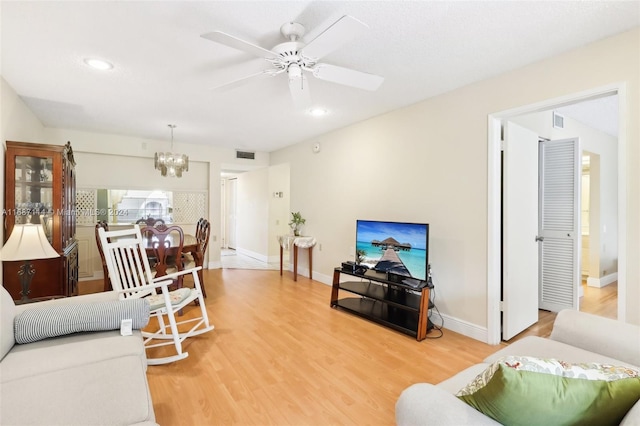 living room with wood-type flooring and ceiling fan with notable chandelier