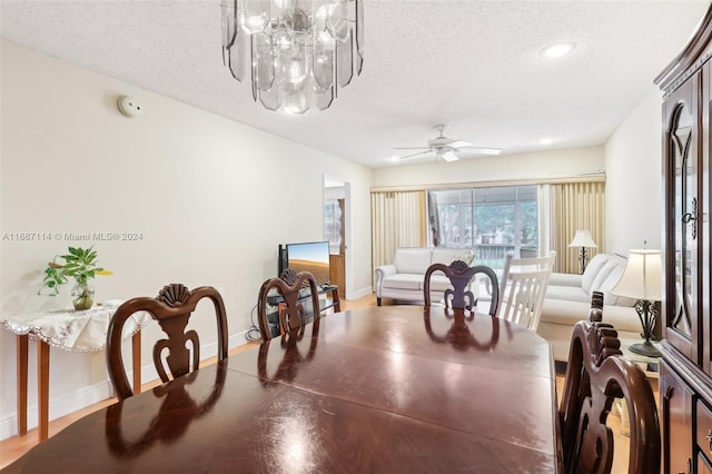 dining area featuring ceiling fan with notable chandelier and a textured ceiling