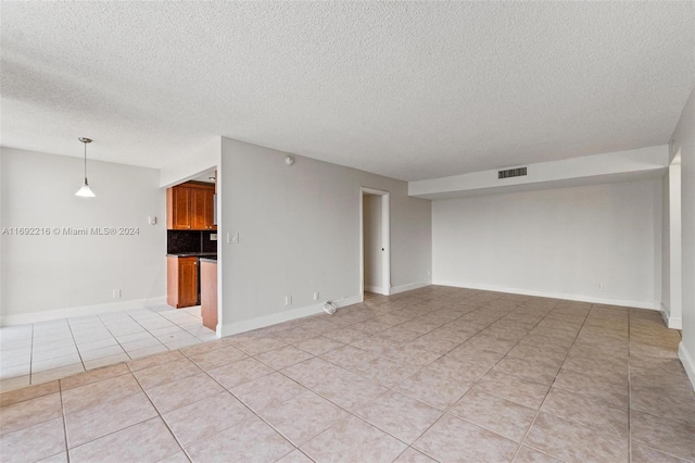 empty room with light tile patterned floors and a textured ceiling