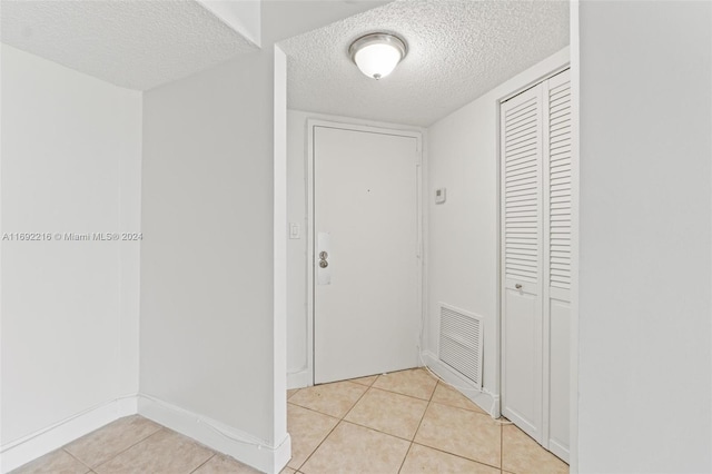 doorway featuring light tile patterned floors and a textured ceiling