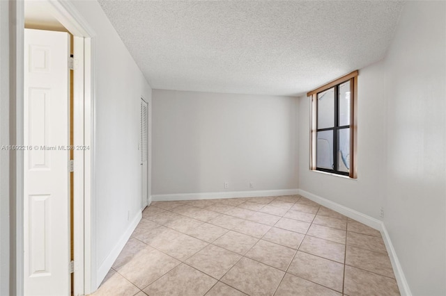 empty room with light tile patterned floors and a textured ceiling