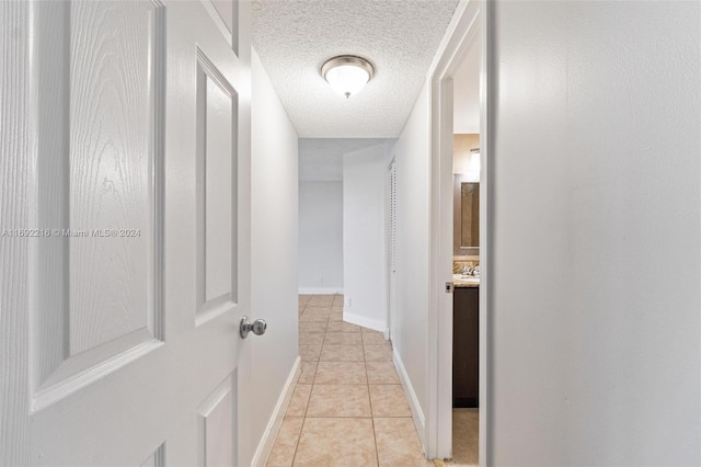 hall with light tile patterned floors and a textured ceiling