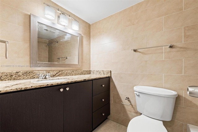 bathroom featuring tiled shower, vanity, toilet, and tile walls