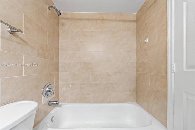 bathroom with toilet and tiled shower / bath