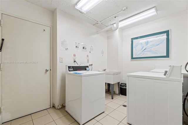 laundry room with sink, light tile patterned floors, a textured ceiling, and washing machine and clothes dryer