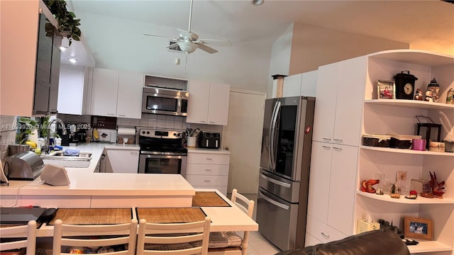 kitchen with white cabinetry, sink, stainless steel appliances, kitchen peninsula, and decorative backsplash