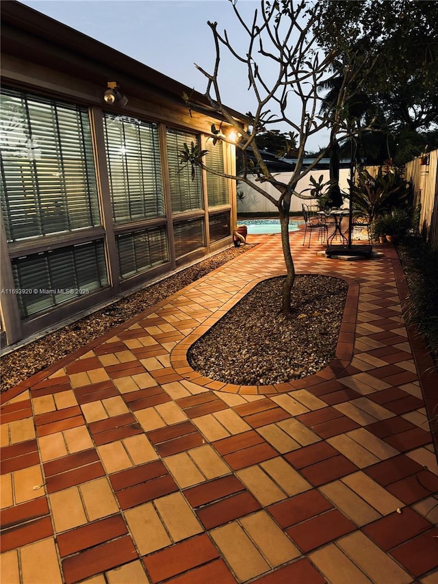 patio terrace at dusk featuring a fenced in pool