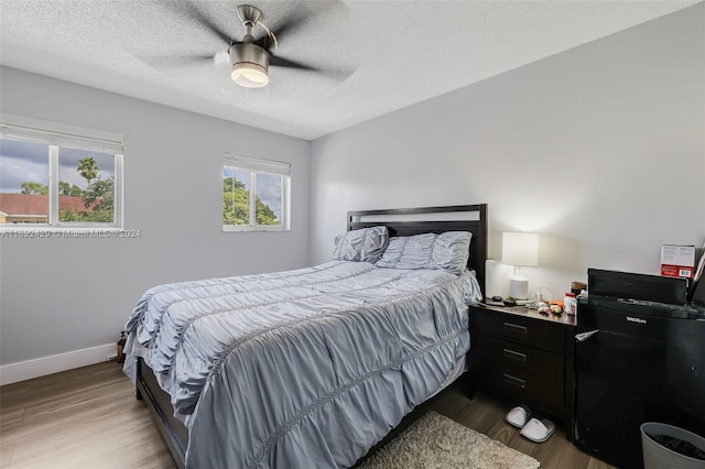 bedroom featuring ceiling fan, wood-type flooring, and a textured ceiling