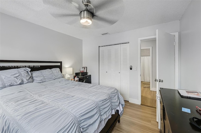 bedroom featuring ceiling fan, a closet, light hardwood / wood-style floors, and a textured ceiling