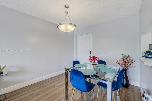 dining room with hardwood / wood-style floors and a textured ceiling