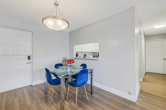 dining area with a textured ceiling and light hardwood / wood-style flooring