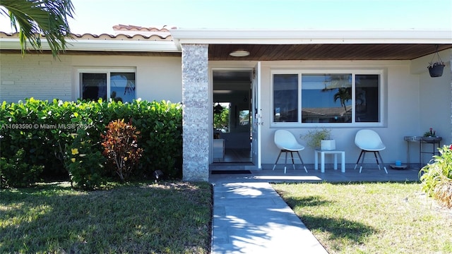 view of exterior entry featuring a lawn