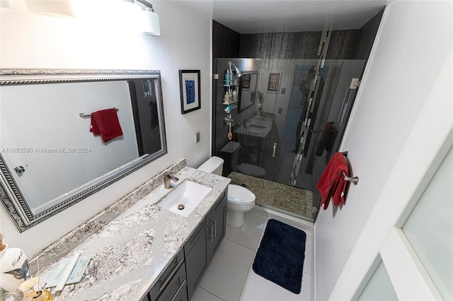 bathroom featuring tile patterned flooring, vanity, a shower with shower door, and toilet