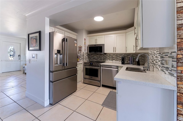 kitchen with sink, light tile patterned floors, appliances with stainless steel finishes, tasteful backsplash, and white cabinetry