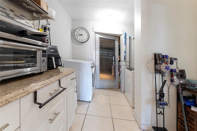 kitchen featuring white cabinets, light tile patterned floors, and washing machine and dryer