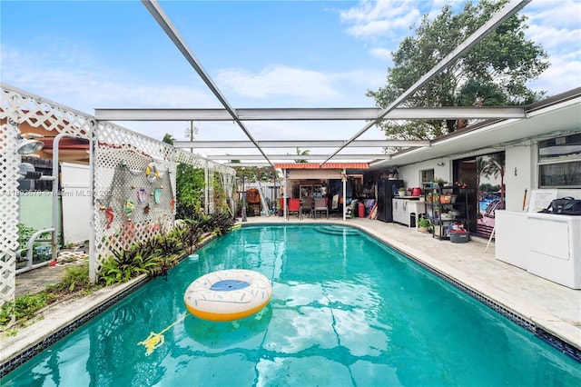 view of swimming pool featuring washer / dryer, a patio, and glass enclosure