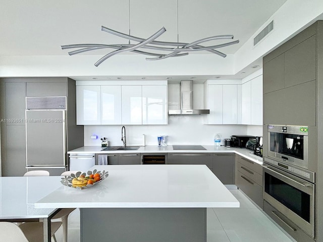 kitchen featuring gray cabinetry, stainless steel appliances, sink, wall chimney range hood, and light tile patterned floors