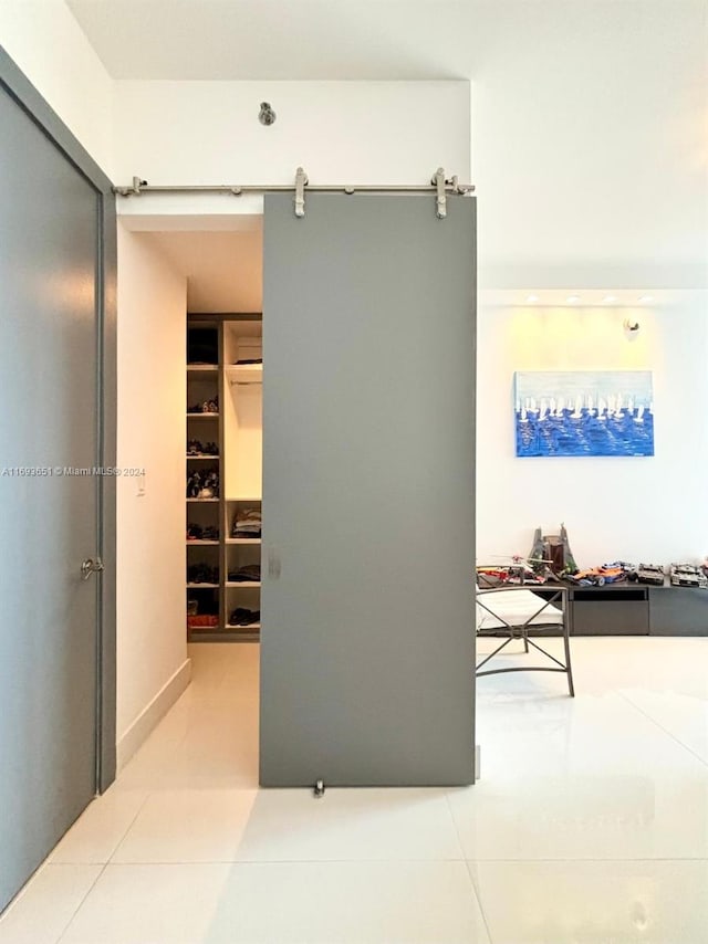 hall with a barn door and light tile patterned floors