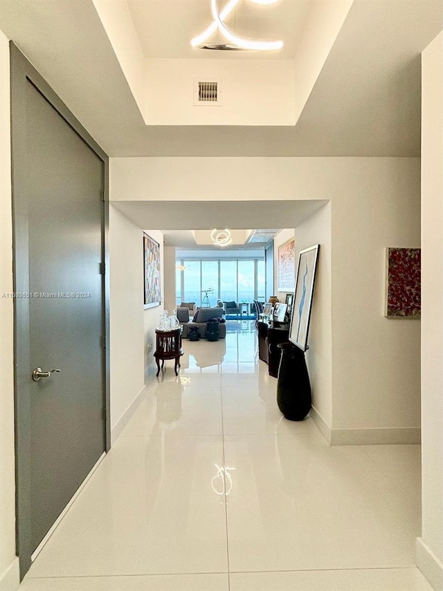 hall featuring a tray ceiling and tile patterned flooring