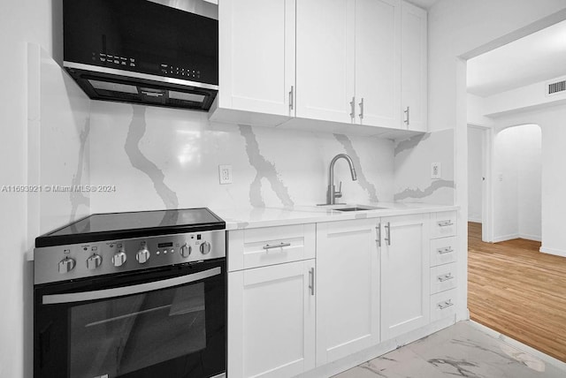 kitchen featuring stove, white cabinets, light wood-type flooring, and sink